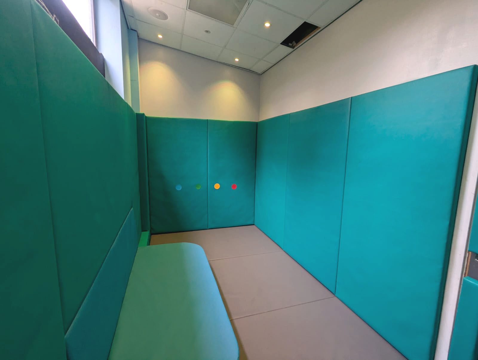 De-escalation room with safety padding and calming lighting for crisis support